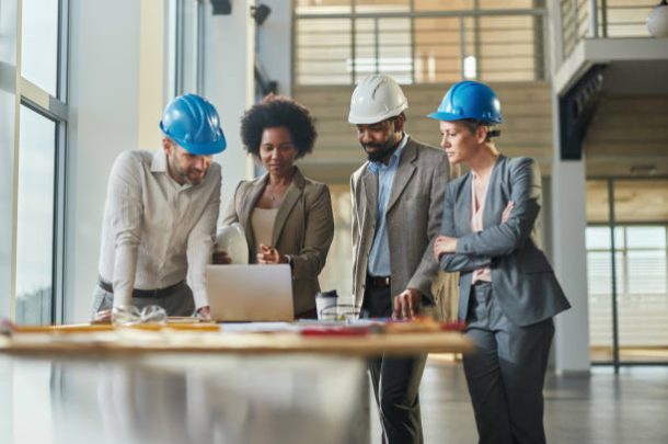 Group of diverse project managers cooperating while working on a computer at construction building.